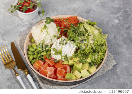 Salad bowl with rice, salmon, tomatoes, cucumbers and avocado. Poached egg. Salad bowl with rice, salmon, tomatoes, cucumbers and avocado. Poached egg. 115496997