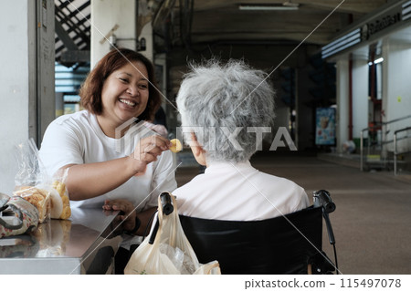 A young woman is feeding her elderly mother. 115497078