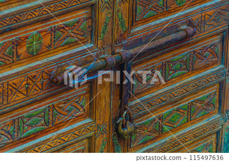 Big old wooden door decorated with various symbolic signs carved directly on the canvas of massif. Example of exterior and interior decoration of entrance lobbies in different cultures around world Big old wooden door decorated with various symbolic signs carved directly on the canvas of massif. Example of exterior and interior decoration of entrance lobbies in different cultures around world 115497636