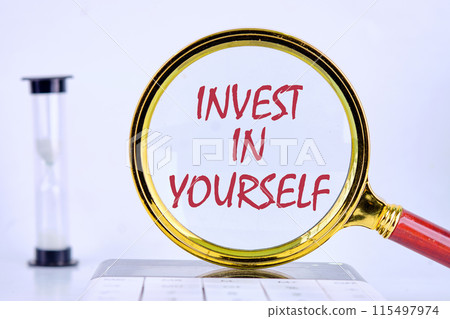 Business and Invest in yourself concept. Copy space. Concept words Invest in yourself through a magnifying glass standing on a calculator in an hourglass composition 115497974