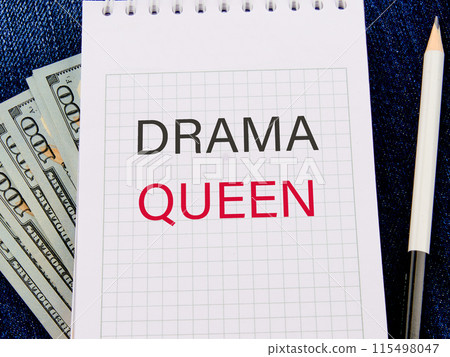Text DRAMA QUEEN in a notebook in a composition with American hundred dollar bills and a pencil 115498047