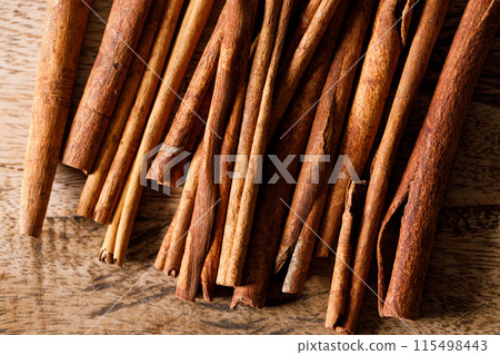 Cinnamon sticks dried tree bark spice on rustic wooden table background. Selective focus. Cinnamon sticks dried tree bark spice on rustic wooden table background. Selective focus. 115498443