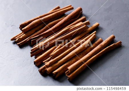 Cinnamon sticks dried tree bark spice on black stone table background. Selective focus. 115498459