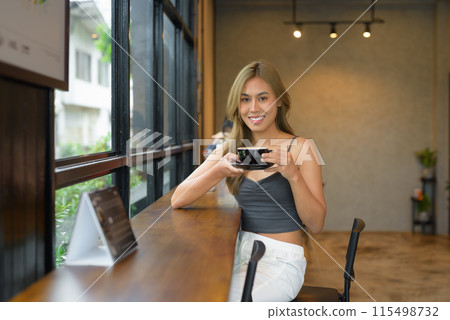 Portrait of beautiful young woman happily holding coffee cup 115498732