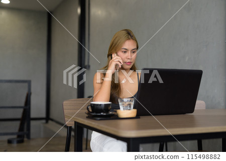 Beautiful woman sitting in cafe wearing professional clothing while using laptop computer 115498882