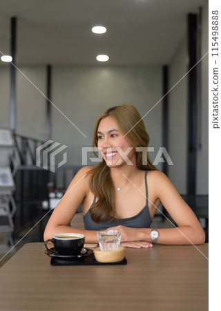 Portrait of beautiful young woman sitting in cafe relaxing and wearing professional clothing 115498888