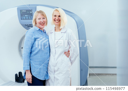 A woman and a doctor are posing in front of a medical machine. The woman is smiling and the doctor is wearing a white coat. Concept of warmth and friendliness 115498977
