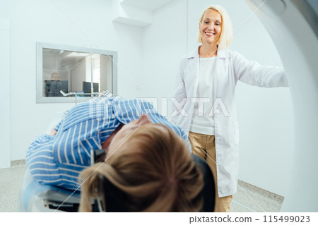 A woman in a white coat stands next to a woman in a blue shirt in a room with a medical machine A woman in a white coat stands next to a woman in a blue shirt in a room with a medical machine 115499023