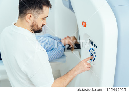 Male medical professional helping mature woman in CT scanner. 115499025
