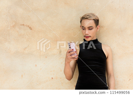 Asian queer LGBT community supporter man with mustache wearing lipstick and jumpsuit using phone 115499056