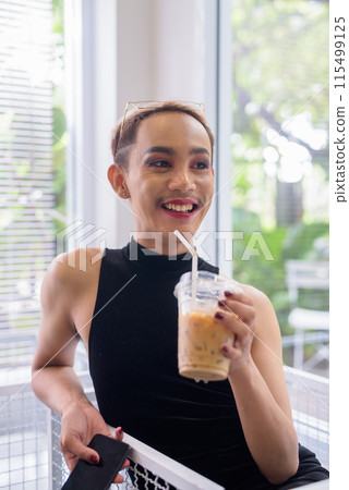 Beautiful Asian queer LGBT community supporter man drinking iced coffee indoors Beautiful Asian queer LGBT community supporter man drinking iced coffee indoors 115499125