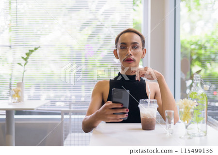 Beautiful Asian queer LGBT community supporter man sitting in coffee shop using phone 115499136