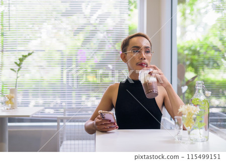 Beautiful Asian queer LGBT community supporter man using mobile phone in coffee shop Beautiful Asian queer LGBT community supporter man using mobile phone in coffee shop 115499151
