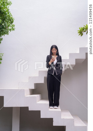 Full length portrait of a professional woman in business attire on modern architectural steps Full length portrait of a professional woman in business attire on modern architectural steps 115499456