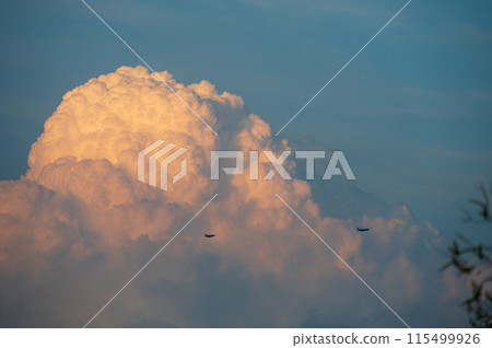 兩架飛機在夕陽染紅的雲朵前飛過 115499926