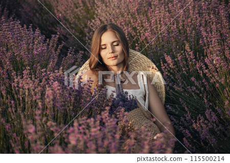 A woman is sitting in a field of lavender flowers. She is wearing a straw hat and holding a basket of flowers. The scene is peaceful and serene, with the woman enjoying the beauty of the flowers. 115500214