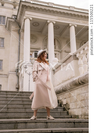 A woman in a hat stands on a set of stairs in front of a building. She is wearing a coat and a skirt. A woman in a hat stands on a set of stairs in front of a building. She is wearing a coat and a skirt. 115500221