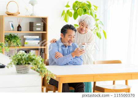 Senior couple looking at a smartphone in the living room 115500370