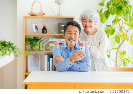 Senior couple looking at a smartphone in the living room 115500371