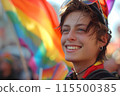 A young man is smiling and holding a rainbow flag 115500385