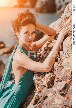 Woman green dress sea. Woman in a long mint dress posing on a beach with rocks on sunny day. Girl on the nature on blue sky background. Woman green dress sea. Woman in a long mint dress posing on a beach with rocks on sunny day. Girl on the nature on blue sky background. 115500395
