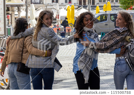 Friends in casual attire, hugging, laughing, and having fun on a sunny day in a city square Friends in casual attire, hugging, laughing, and having fun on a sunny day in a city square 115500788