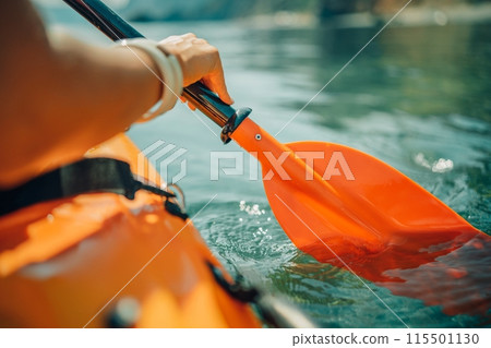 Kayak paddle sea vacation. Person paddles with orange paddle oar on kayak in sea. Leisure active lifestyle recreation activity rest tourism travel Kayak paddle sea vacation. Person paddles with orange paddle oar on kayak in sea. Leisure active lifestyle recreation activity rest tourism travel 115501130