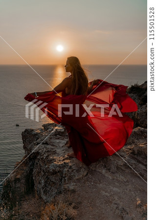 Woman sunset sea red dress, side view a happy beautiful sensual woman in a red long dress posing on a rock high above the sea on sunset. 115501528