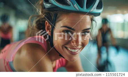 Smiling woman in helmet, cyclist athlete training in the gym, preparing for upcoming competition. Tour de France 115501724