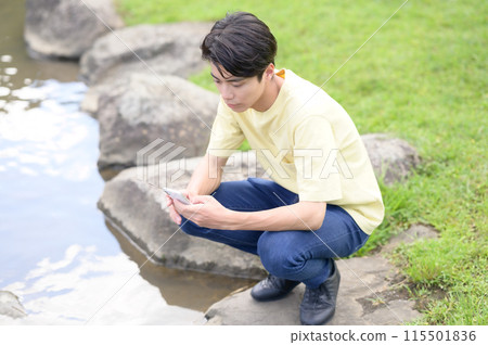 A young man operating a smartphone by the water A young man operating a smartphone by the water 115501836