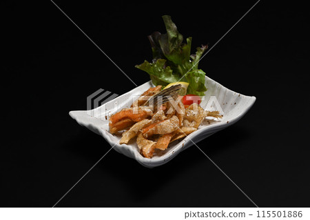 Delicious fried salmon belly in white ceramic plate isolate on black background. Appetizer and Japanese food concept Delicious fried salmon belly in white ceramic plate isolate on black background. Appetizer and Japanese food concept 115501886