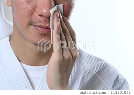Man wearing bathrobe using cotton pads and cleansing product isolate on white background. Self care concept 115501951