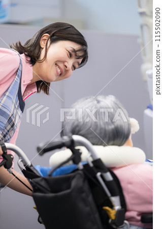 照顧坐在輪椅上的老人的形象，微笑的護理人員的特寫，垂直 115502090