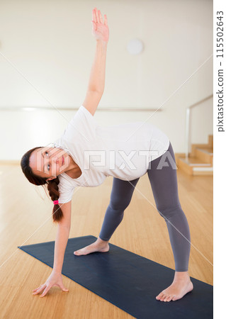 Pregnant woman is engaged in yoga. Elongated Triangle Pose or Utthita Trikonasana 115502643