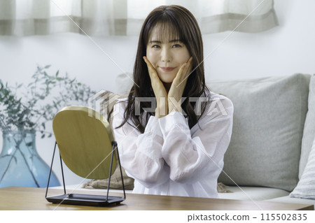 年輕女子手放在臉頰上看著鏡子微笑 115502835