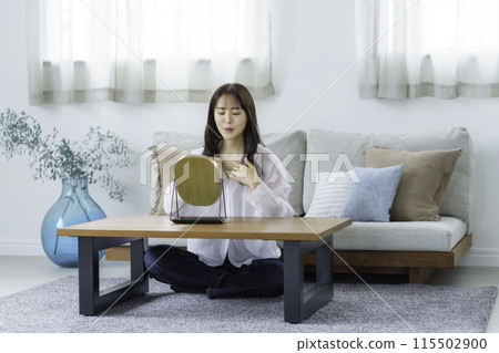 A young woman checking her chest in the mirror in the living room 115502900