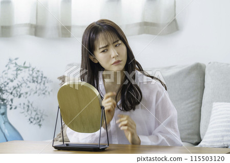 一個年輕女子看著鏡子，看起來很擔心 115503120