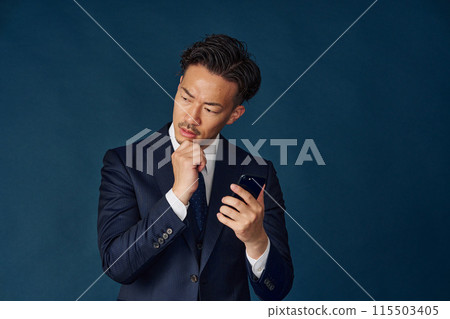 Businessman thinking with a smartphone 115503405