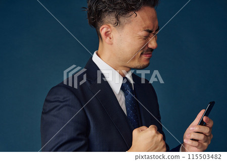 A businessman posing with a smartphone 115503482