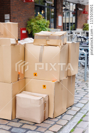 Many paper cardboard boxes on downtown street german city. Parcel delivery shipment courier logistics service. Office or home moving package scene Many paper cardboard boxes on downtown street german city. Parcel delivery shipment courier logistics service. Office or home moving package scene 115503601