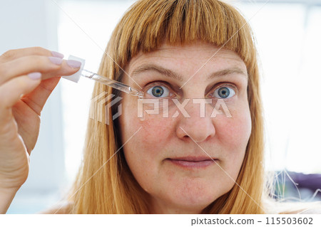 face middle-aged woman close-up, blonde, applying cosmetic product against aging skin 115503602