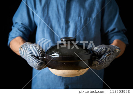 一個男人拿著一個陶鍋煮飯 115503938