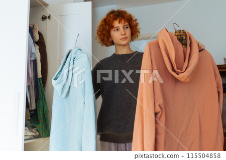 Teenager girl looking at clothes in wardrobe Teenager girl looking at clothes in wardrobe 115504858