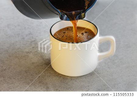 Pouring coffee from cezve in cup on white background Pouring coffee from cezve in cup on white background 115505333