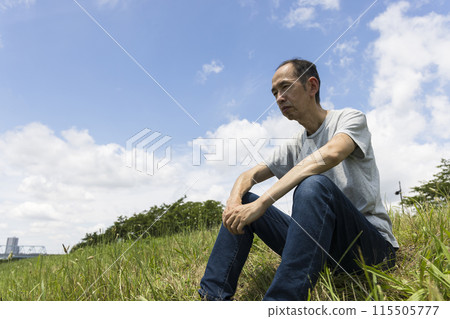 Middle-aged man sitting on the riverbank 115505777