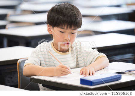Elementary school boy studying and holding a pencil during class in the classroom 115506168