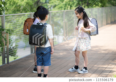 A girl in her class talking to her friends while carrying a school bag 115506179