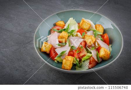 Close-up of salad with ham and halloumi cheese in a bowl on the table 1 115506748
