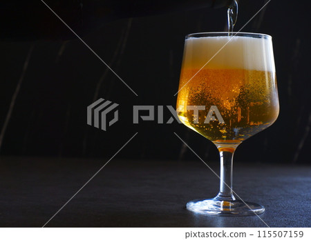 將冰鎮啤酒倒入玻璃杯中 將冰鎮啤酒倒入玻璃杯中 115507159