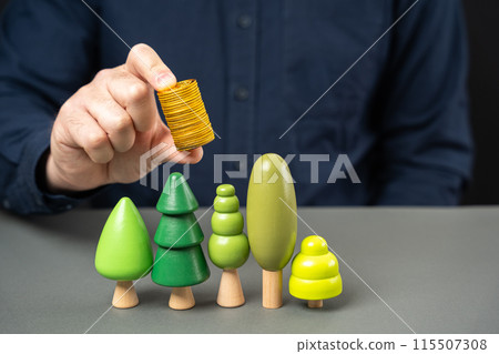 Businessman holding coins over trees. Green bonds. The concept of investment in the development of city parks and the planting of greenery and plants. Fresh air Caring for nature Businessman holding coins over trees. Green bonds. The concept of investment in the development of city parks and the planting of greenery and plants. Fresh air Caring for nature 115507308